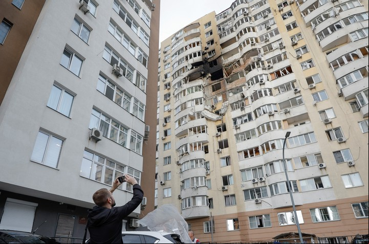 Un hombre saca una foto a un edificio bombardeado por Moscú  en Kiev. Foto: EFE